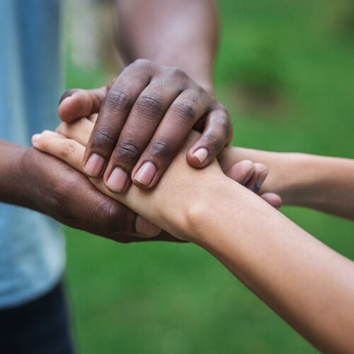 Black caregiver supporting woman hand in park