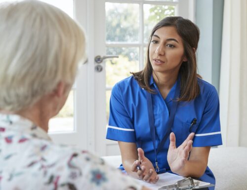 Senior woman talking to young care nurse on home visit